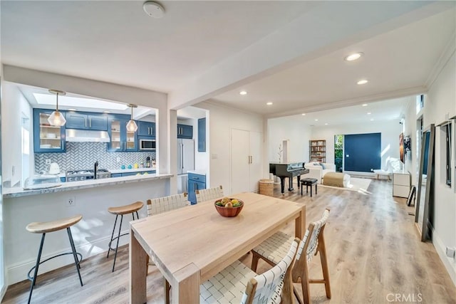 dining area featuring ornamental molding, light wood-type flooring, and recessed lighting