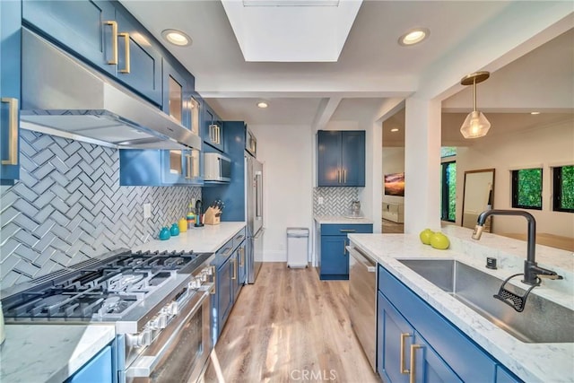 kitchen featuring blue cabinets, appliances with stainless steel finishes, a sink, and under cabinet range hood