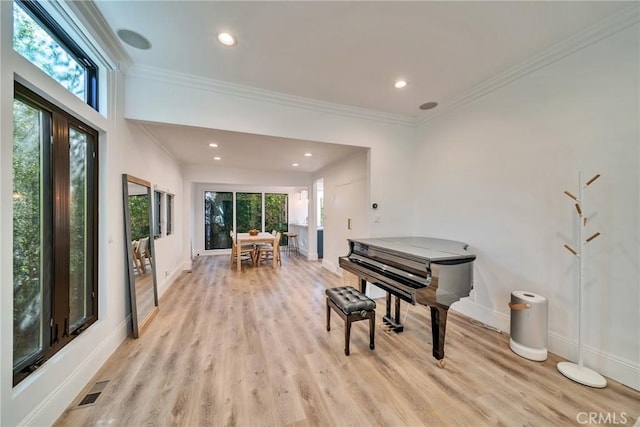 living area featuring baseboards, ornamental molding, and light wood-style floors