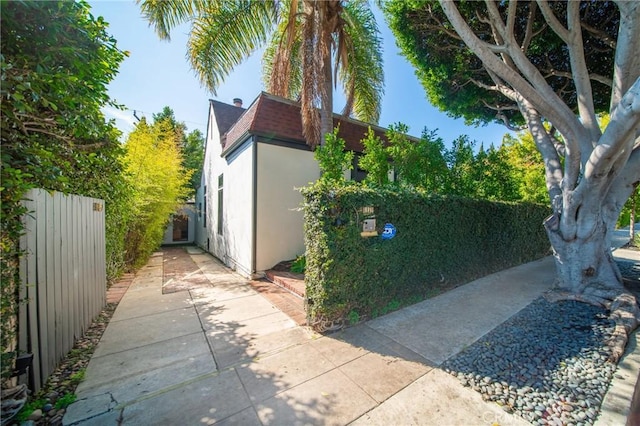 view of side of property featuring fence and stucco siding