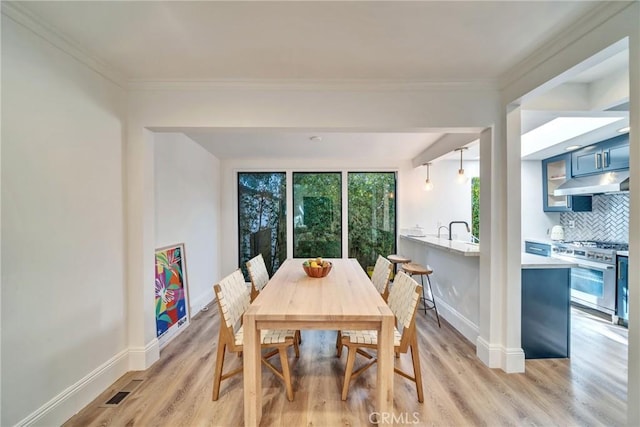 dining space with crown molding, baseboards, visible vents, and light wood-style floors