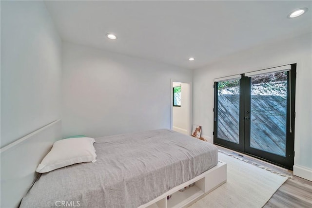 bedroom with recessed lighting, wood finished floors, baseboards, access to exterior, and french doors