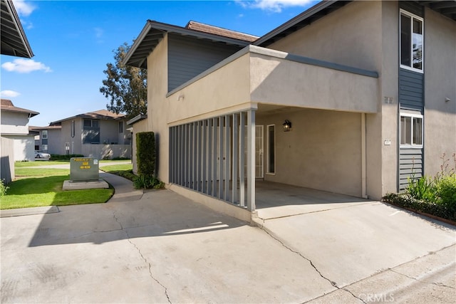 exterior space featuring stucco siding, a residential view, and concrete driveway