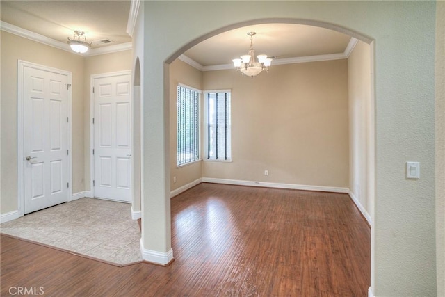 foyer entrance featuring arched walkways, crown molding, visible vents, wood finished floors, and baseboards