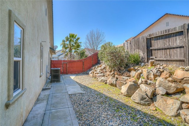 view of yard with a fenced backyard, central AC unit, and a patio