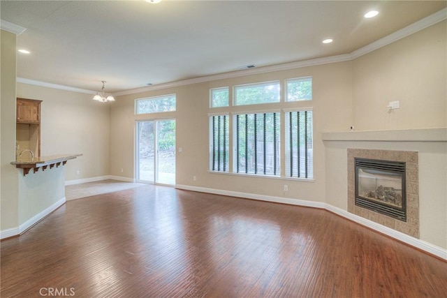 unfurnished living room featuring baseboards, a tile fireplace, ornamental molding, wood finished floors, and recessed lighting