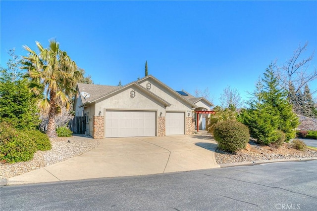 view of front facade with driveway, stone siding, an attached garage, roof mounted solar panels, and stucco siding