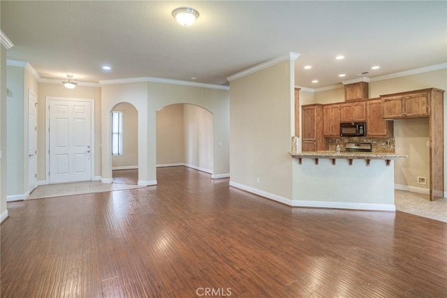 unfurnished living room featuring arched walkways, light wood finished floors, crown molding, and baseboards