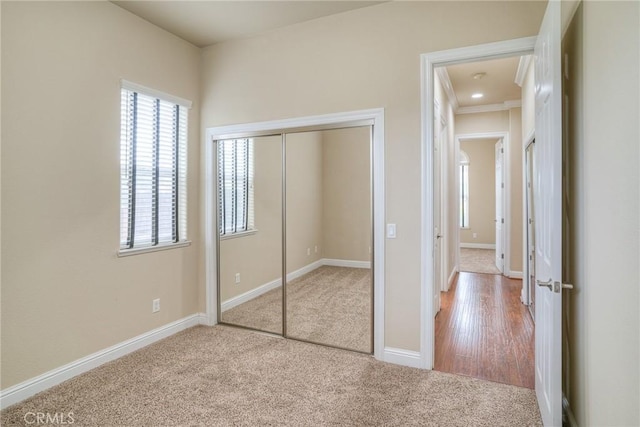 unfurnished bedroom featuring carpet, baseboards, and a closet