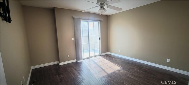 spare room featuring dark wood-style floors, a ceiling fan, and baseboards