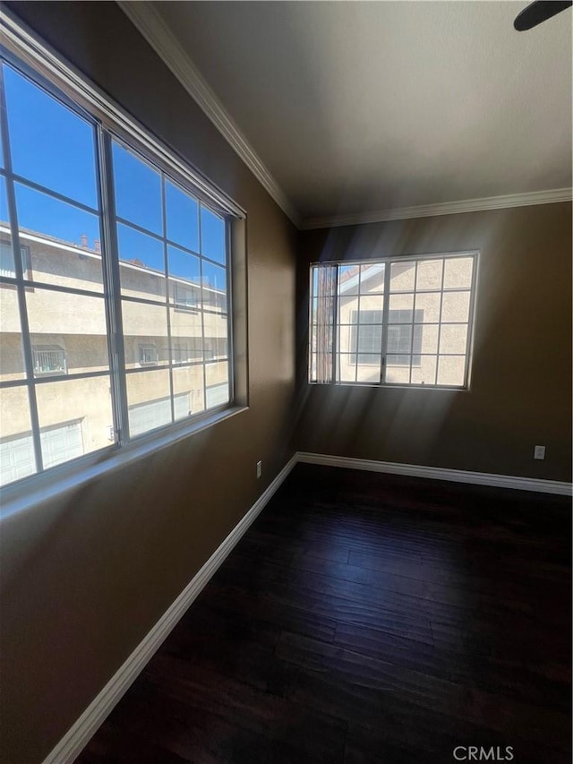 unfurnished room with baseboards, dark wood-type flooring, and crown molding