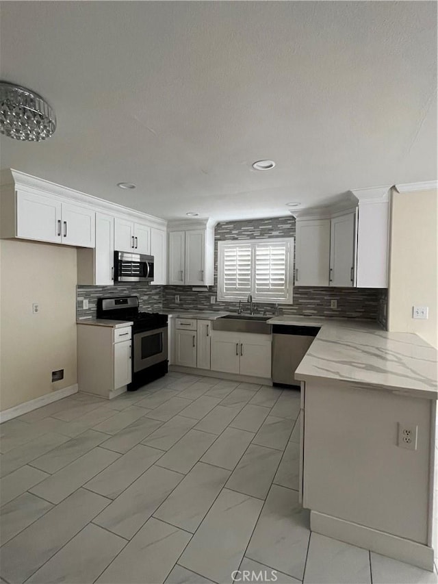 kitchen with decorative backsplash, white cabinets, appliances with stainless steel finishes, and a sink