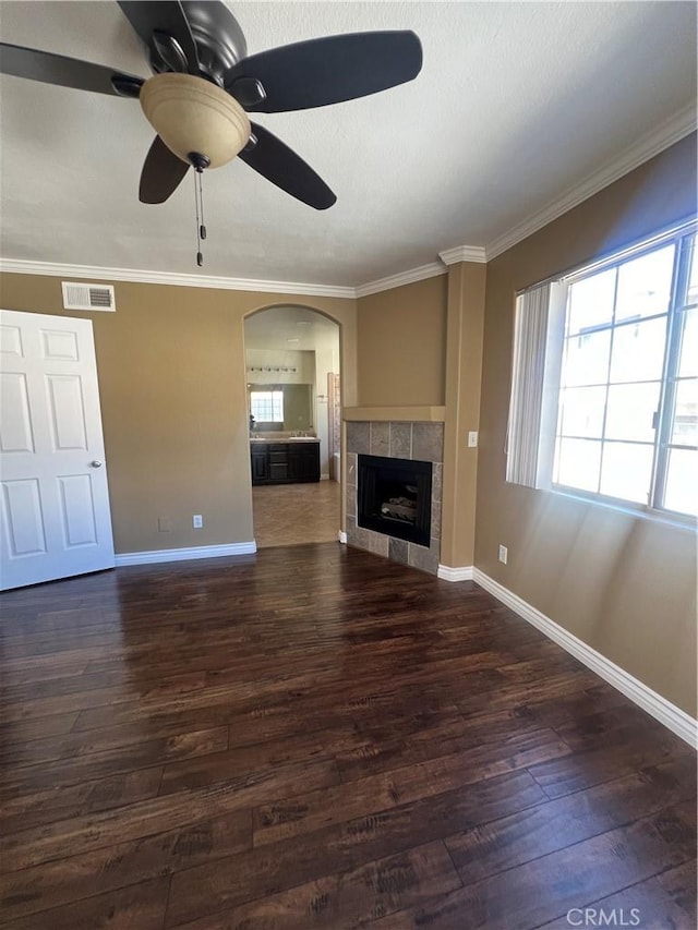 unfurnished living room featuring a tiled fireplace, visible vents, a healthy amount of sunlight, and wood finished floors