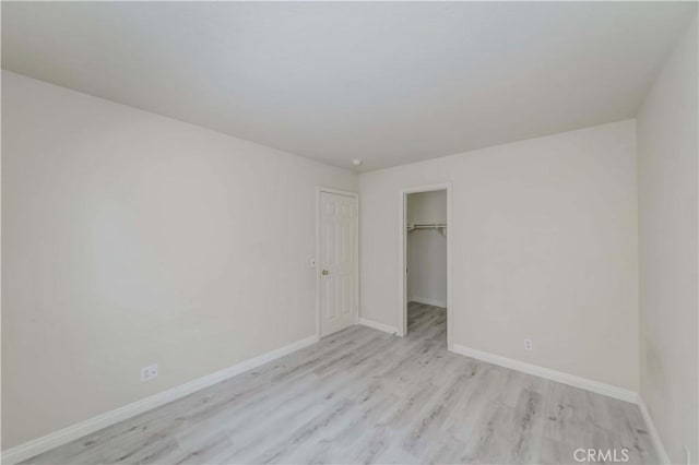 interior space featuring light wood-style floors, a spacious closet, baseboards, and a closet