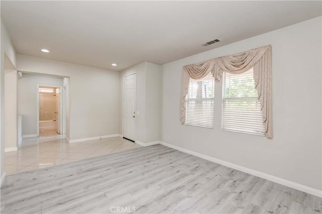 unfurnished room with light wood-type flooring, baseboards, visible vents, and recessed lighting