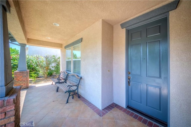 entrance to property with covered porch and stucco siding