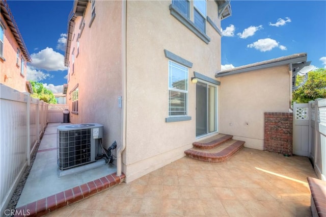 exterior space featuring cooling unit, a patio area, a fenced backyard, and stucco siding