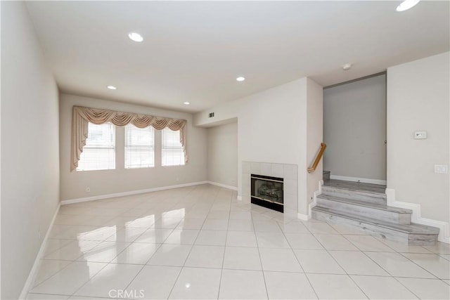 unfurnished living room featuring light tile patterned floors, recessed lighting, baseboards, stairway, and a tiled fireplace