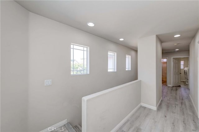 corridor with baseboards, washer / clothes dryer, an upstairs landing, light wood-type flooring, and recessed lighting