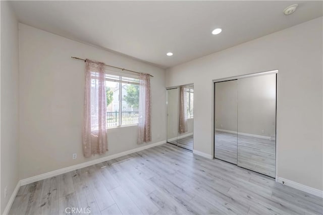 unfurnished bedroom with multiple closets, light wood-type flooring, baseboards, and recessed lighting