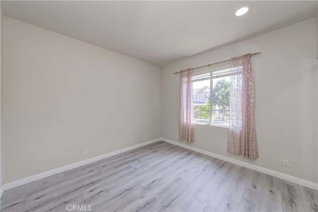 empty room featuring light wood-type flooring, baseboards, and recessed lighting