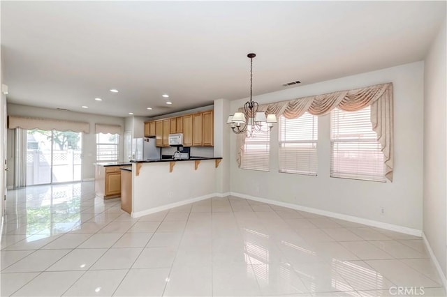 kitchen with white appliances, baseboards, visible vents, a kitchen bar, and a notable chandelier