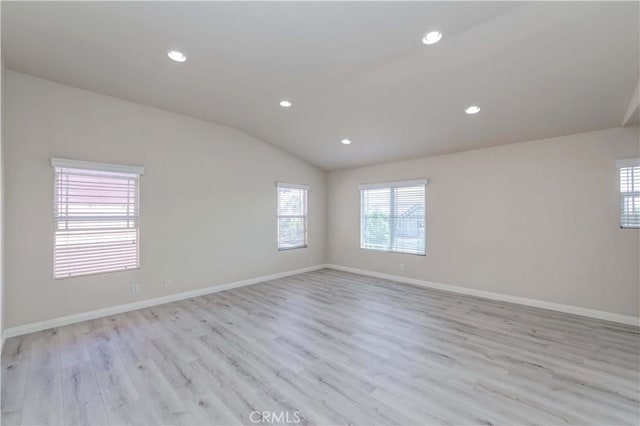 empty room featuring lofted ceiling, light wood-type flooring, baseboards, and recessed lighting