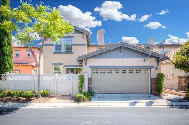 view of front facade with fence, driveway, an attached garage, and stucco siding