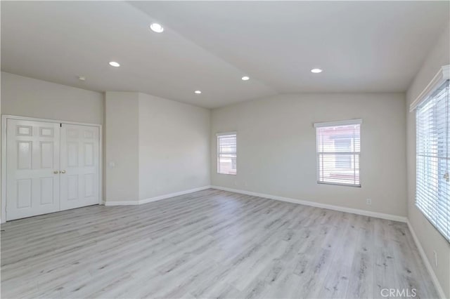 spare room featuring lofted ceiling, light wood finished floors, baseboards, and recessed lighting