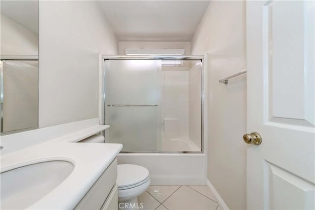 full bathroom with tile patterned flooring, toilet, shower / bath combination with glass door, vanity, and baseboards