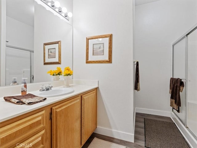 full bath with wood finished floors, a shower stall, vanity, and baseboards