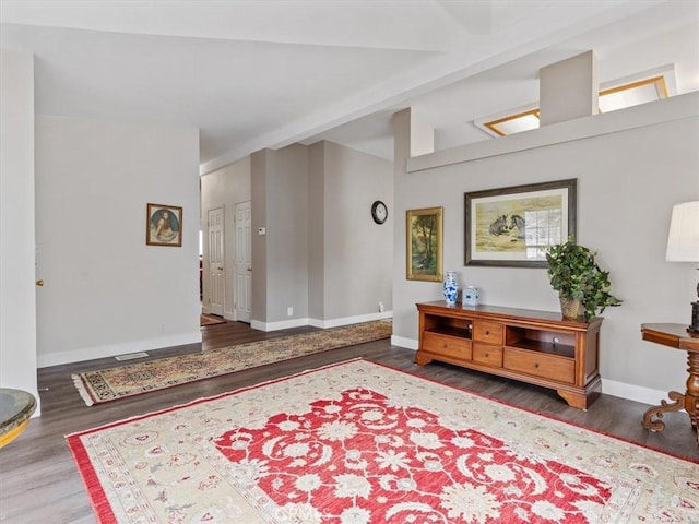 foyer entrance with wood finished floors, beam ceiling, and baseboards