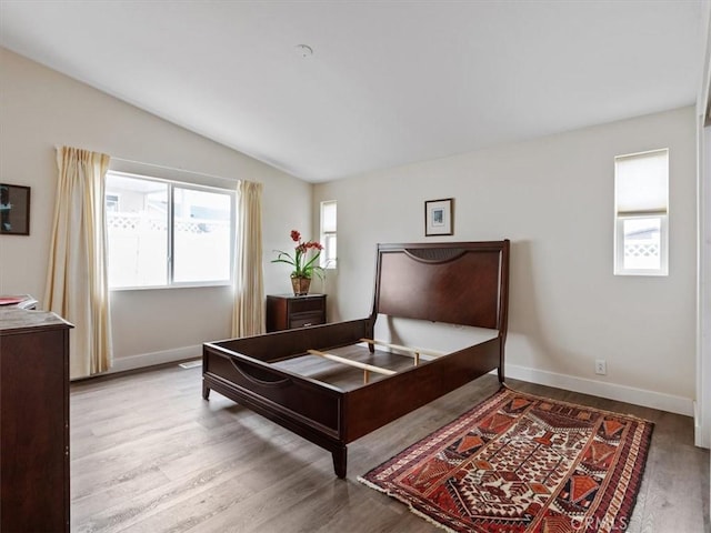 bedroom with lofted ceiling, baseboards, and wood finished floors