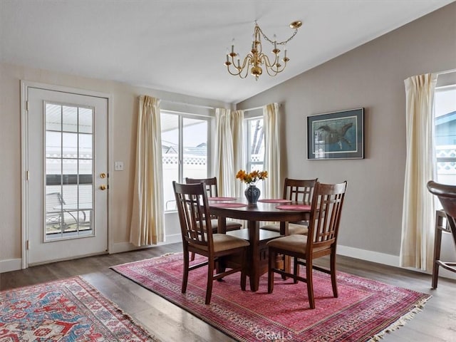 dining space featuring a chandelier, lofted ceiling, baseboards, and wood finished floors