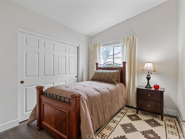 bedroom featuring vaulted ceiling, light wood finished floors, a closet, and baseboards