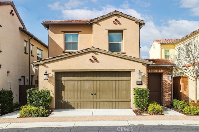 mediterranean / spanish house with a tiled roof, fence, driveway, and stucco siding