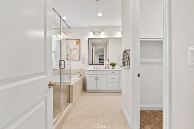 bathroom with a walk in closet, a garden tub, a shower stall, vanity, and tile patterned floors