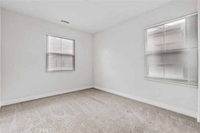 spare room featuring carpet floors, visible vents, and baseboards