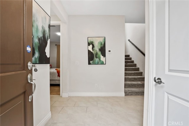 entryway featuring stairway, baseboards, and light tile patterned floors