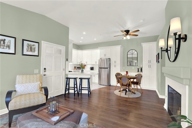 living room featuring a glass covered fireplace, dark wood-style floors, recessed lighting, baseboards, and ceiling fan