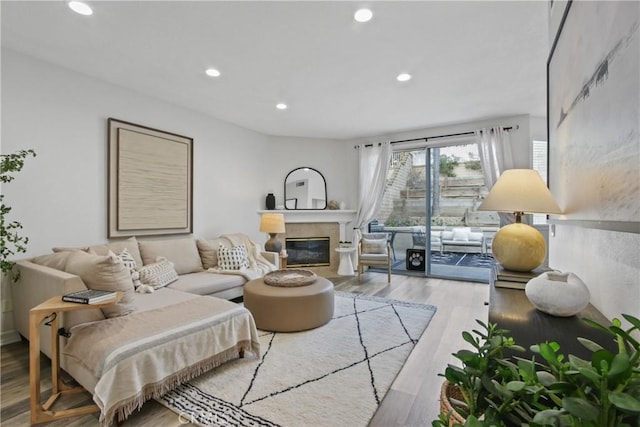 living room featuring a glass covered fireplace, wood finished floors, and recessed lighting