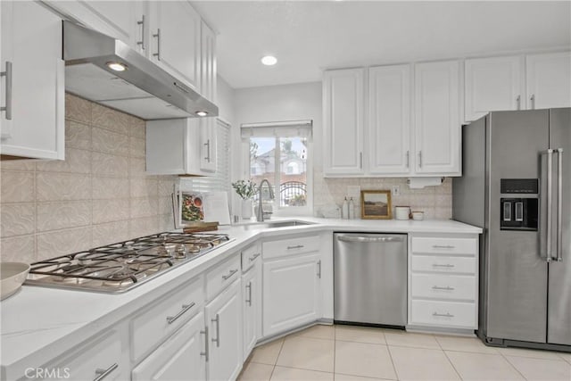 kitchen with stainless steel appliances, light countertops, white cabinets, a sink, and under cabinet range hood