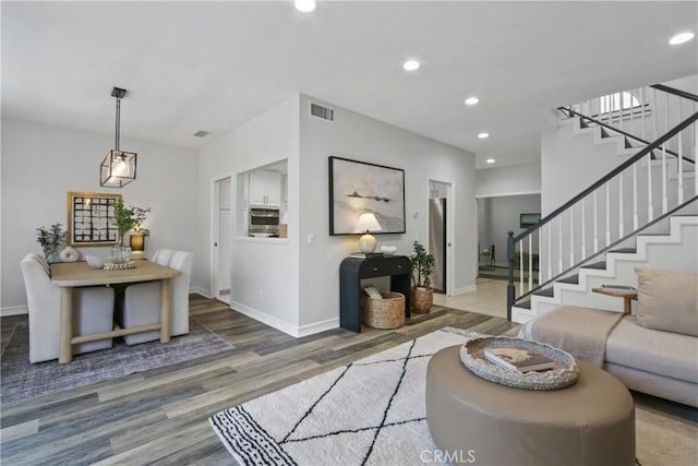 living area with visible vents, baseboards, wood finished floors, stairs, and recessed lighting