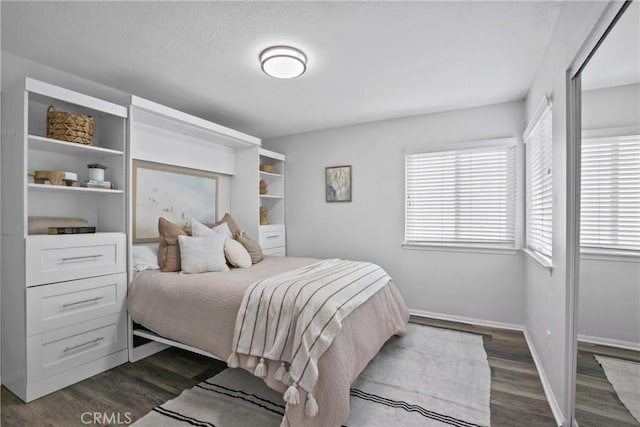 bedroom featuring dark wood-style floors, a textured ceiling, and baseboards