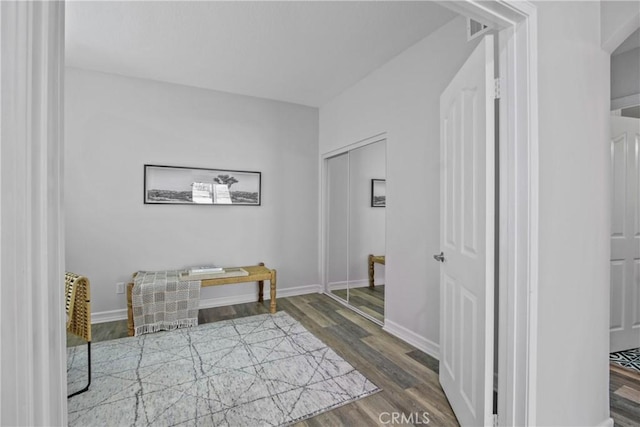 hallway featuring visible vents, baseboards, and wood finished floors