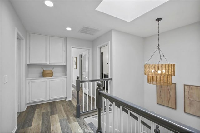 hall with a skylight, visible vents, dark wood-type flooring, an upstairs landing, and recessed lighting