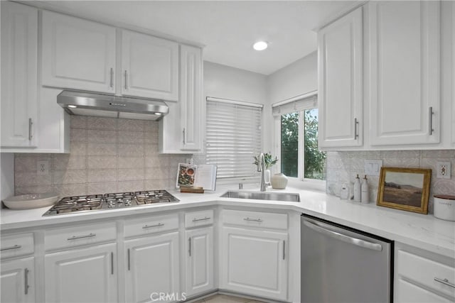 kitchen featuring stainless steel appliances, light countertops, white cabinetry, a sink, and under cabinet range hood