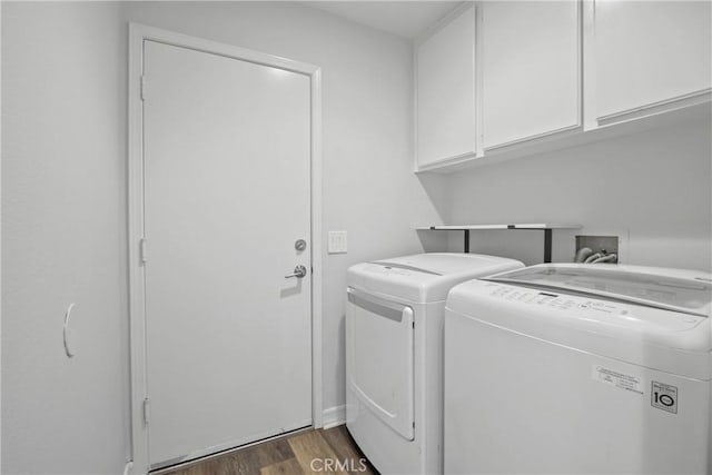 washroom featuring washer and dryer, dark wood-style flooring, and cabinet space