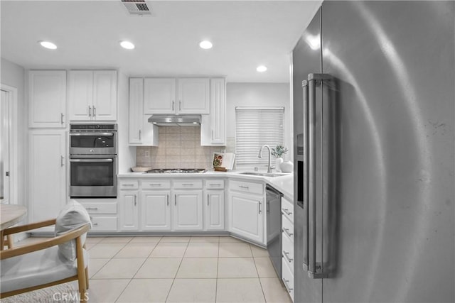 kitchen with visible vents, white cabinets, stainless steel appliances, under cabinet range hood, and a sink