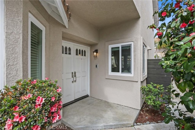 property entrance with fence and stucco siding